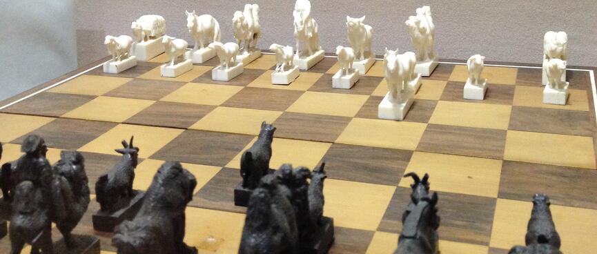 Black and white chess pieces in the shapes of sheep, horses, camels, goats and herders.