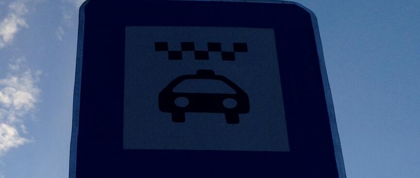 A rectangular sign displays a taxi icon.