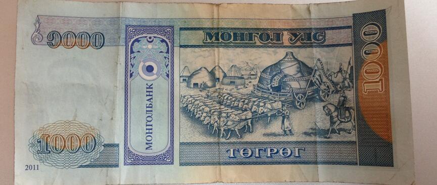 An assembled ger being drawn by a large team of cattle, on the back of a 1000 Tugrik bill.