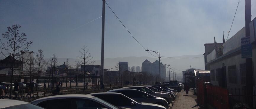 Sun and clear blue sky above a line of parked cars.