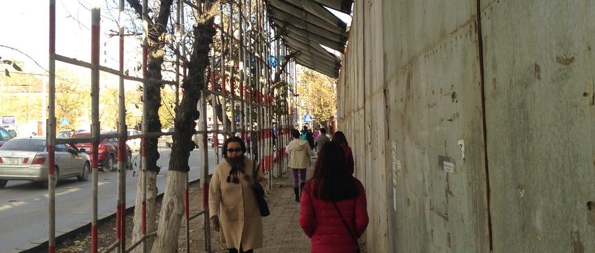Metal poles and sheets of wood support a covered pedestrian walkway.