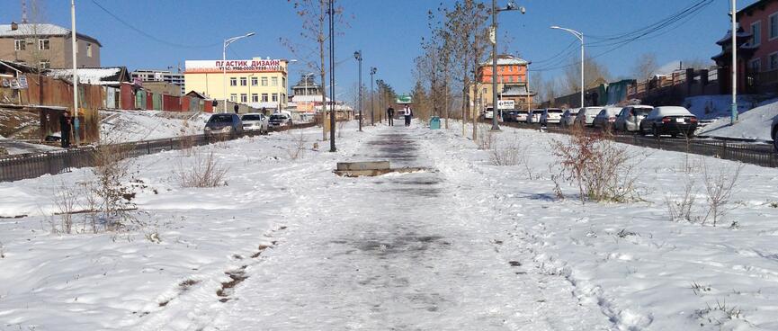 Footprints in the snow on a wide downhill street.