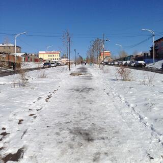 Footprints in the snow on a wide downhill street.
