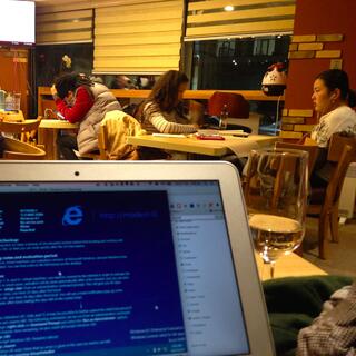 Students study with their earphones in, while music plays through a television.