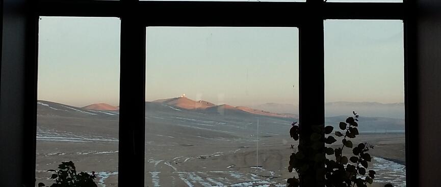 Six window panes frame a view of snowy ground, distant mist and sun kissed mountains.