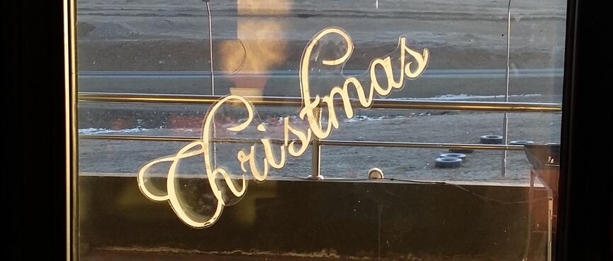 Merry Christmas is diagonally stencilled on a window.