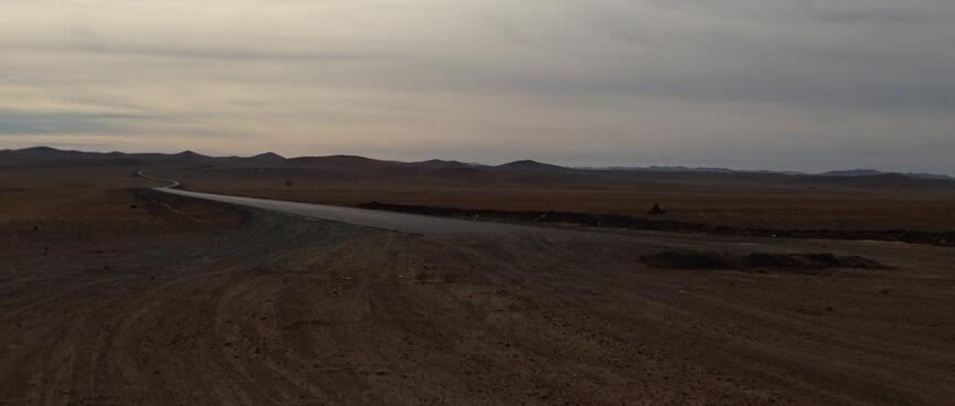 Barren brown steppes extending to low hills at the horizon.