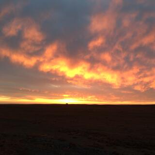 Sunset illuminates the underside of a mottled cloudscape.