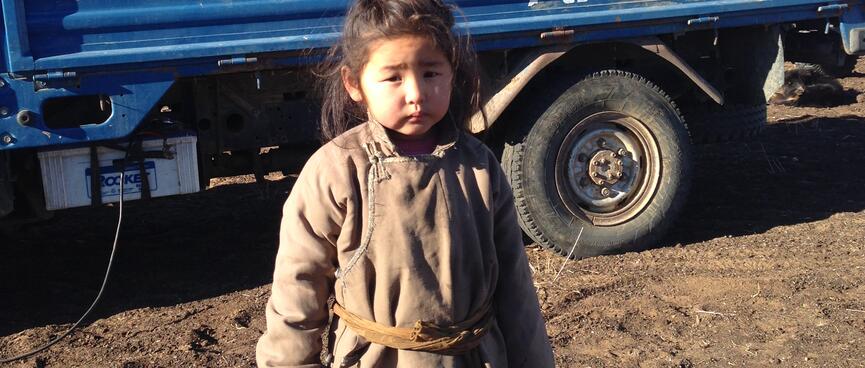 A little girl poses in front of a flatdeck truck.
