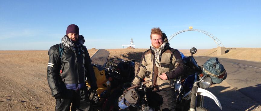 Two men in motorcycling gear pose with our three loaded touring bikes.