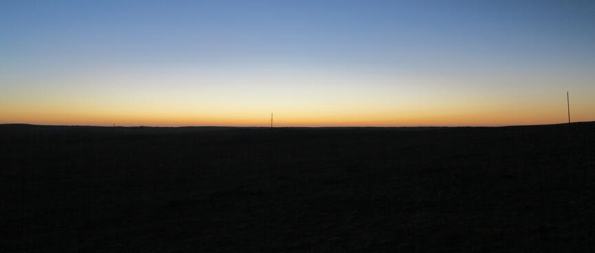 Blue sky and an orange strip above the black horizon.