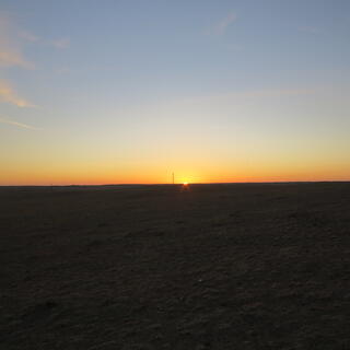 Light blue-orange sky and pinpoint of light at the black horizon.