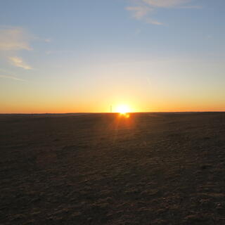 Light blue-orange sky and a bright star at the dark brown horizon.