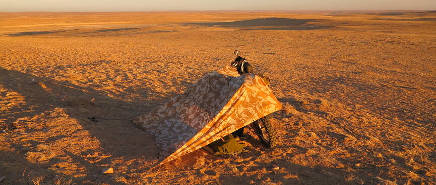 A wedge shaped canvas shelter covered in a repeating brown and yellow pattern.
