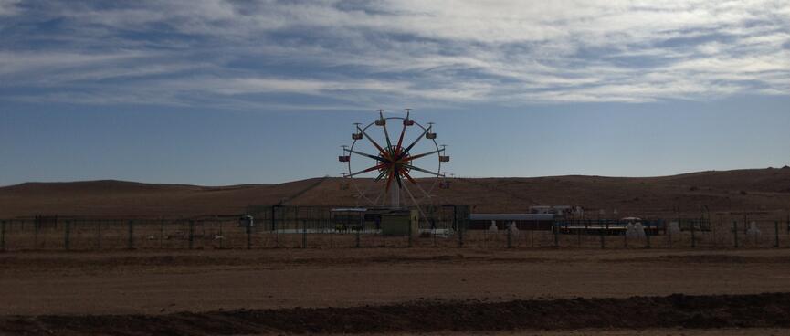 A round ferris wheel with empty chairs.