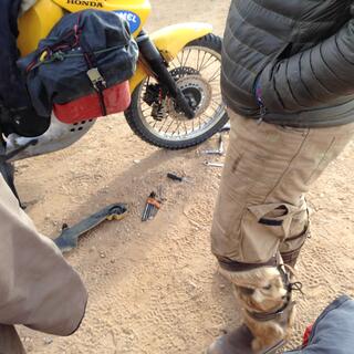 A partial view of legs, wheels and spanners lying in the sand.