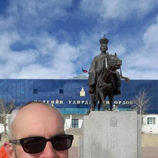 A statue of a horse rider has what looks like a chess pawn on his tall hat.