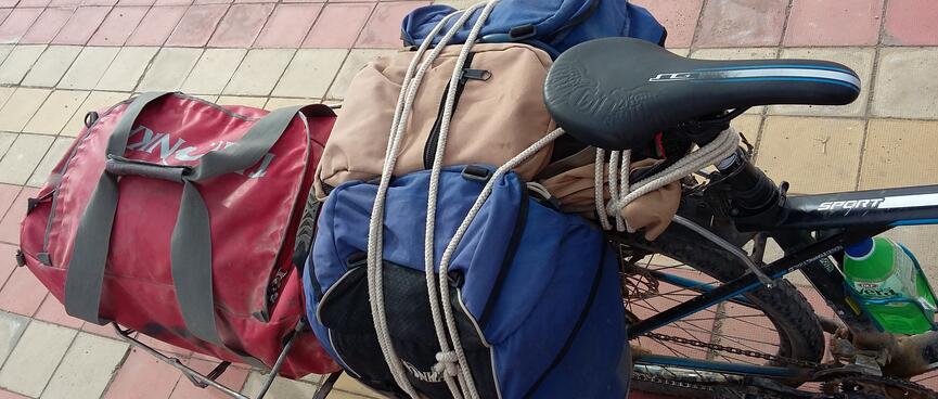Blue and brown packs neatly roped onto the rear rack of a bicycle.
