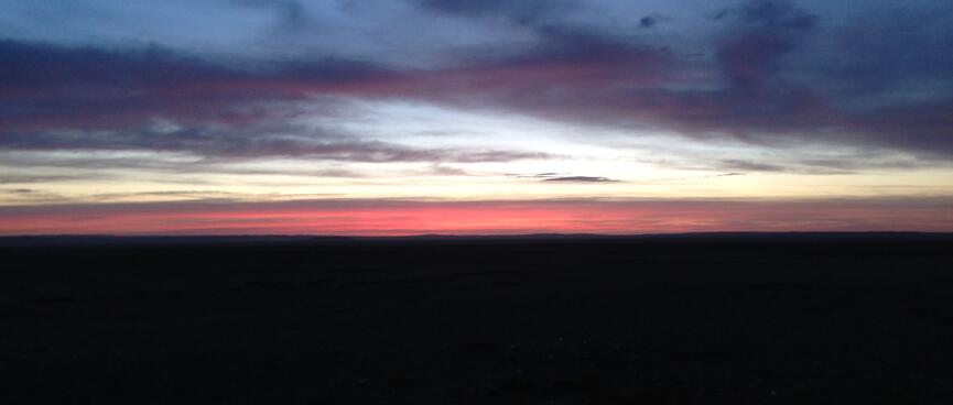 A skyscape with layers of black, pinky-orange, light blue and dark blue.