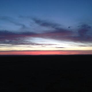 A skyscape with layers of black, pinky-orange, light blue and dark blue.
