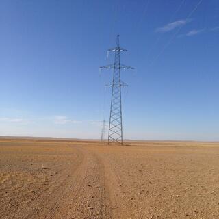 Ahead, a line of tall power pylons extends as far as the eye can see.