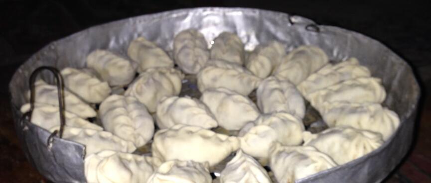 A circular arrangement of raw dumplings in a foil lined pan.