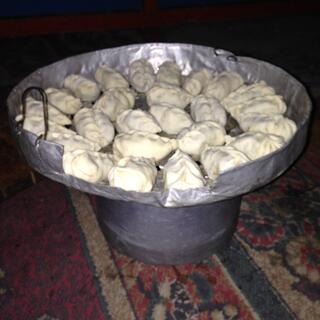 A circular arrangement of raw dumplings in a foil lined pan.
