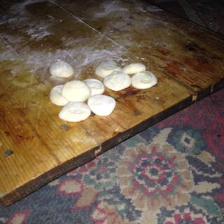 Ten flat buns sitting on a floury table.