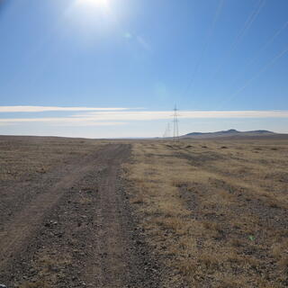 A gravel road through the flat grassy steppe.
