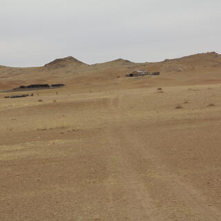 A collection of gers and wooden buildings on a hillside.