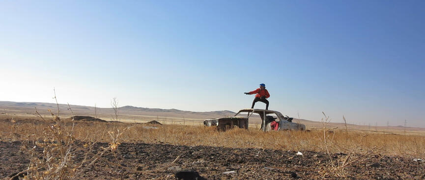 I strike a surfing pose on the roof of a derelict car.