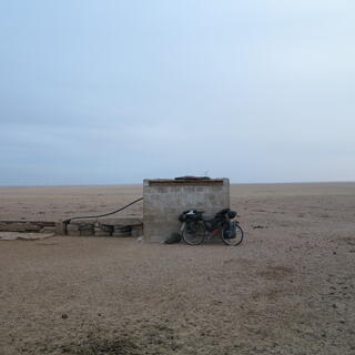 A small brick shed and a long trough to its left.