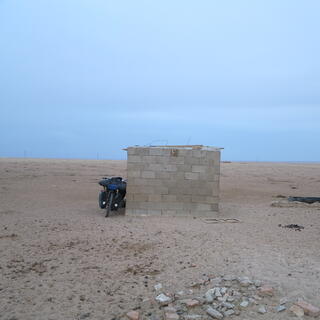 Bike bike leans against a small brick shed.