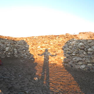 My backlit shadow stretches its arms wide between shadows of walls.