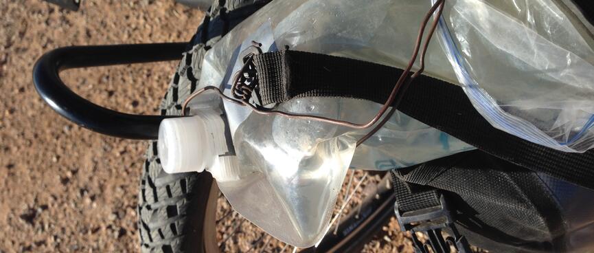 A length of copper wire attached to the neck of a collapsible water bottle.