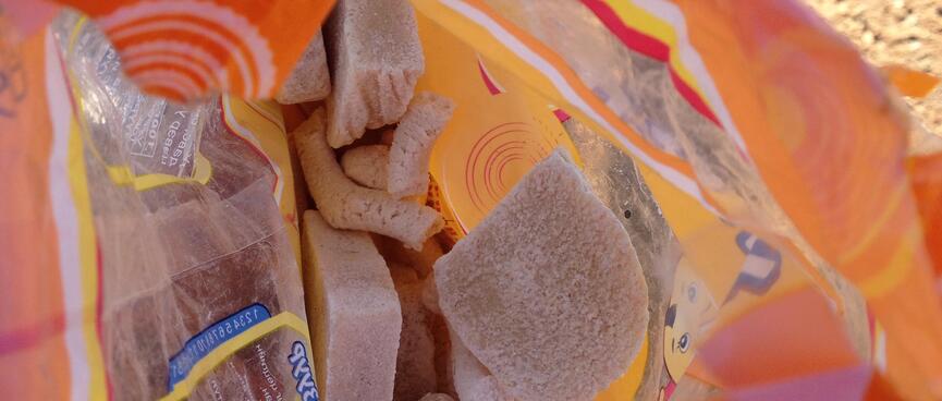 Looking down into an orange plastic bag containing chunks of yellowy-white cheeses.