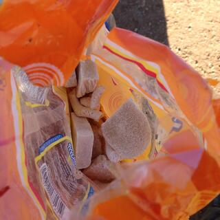 Looking down into an orange plastic bag containing chunks of yellowy-white cheeses.