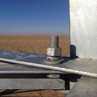 Close-up of a nut and bolt on the metal frame of a power pylon.