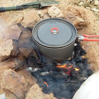 A camping pot sits on top of a pile of flaming animal dung.
