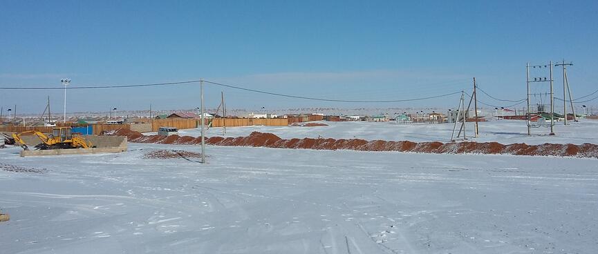 Rows houses of shallow roofed houses behind wooden fences.