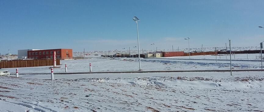Roads and a few buildings, including a two story red brick building, a shipping container and prefabs.