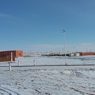 Roads and a few buildings, including a two story red brick building, a shipping container and prefabs.
