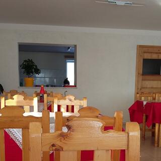 Wooden chairs and tables with red table cloths and white doilies.
