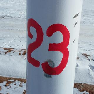 The number 23 is hand painted in red on a white pole.