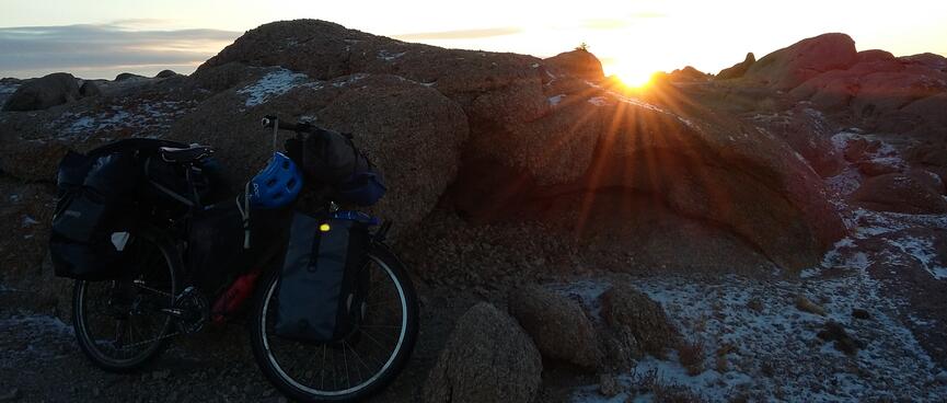 The sun sets over a rocky landscape.