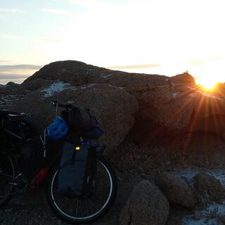 The sun sets over a rocky landscape.