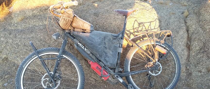My frosted bike leans against a large rock.