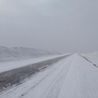 A thin sliver of the clear asphalt in an otherwise snow covered highway.