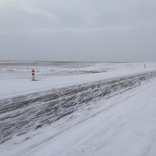 Snow is smeared in all directions on the asphalt highway.