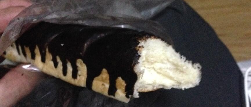 A fluffy bread roll filled with cream and coated in drizzled chocolate.